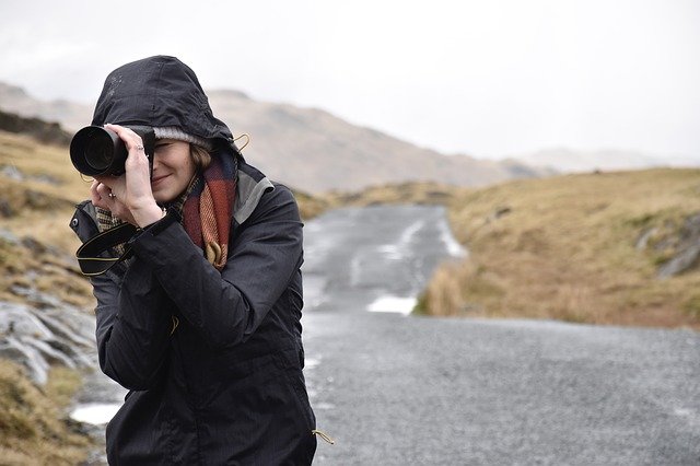 女性が山の上でカメラを向けている